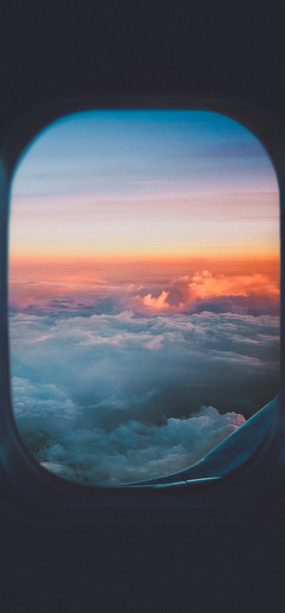 View from airplane window showing sunset over clouds