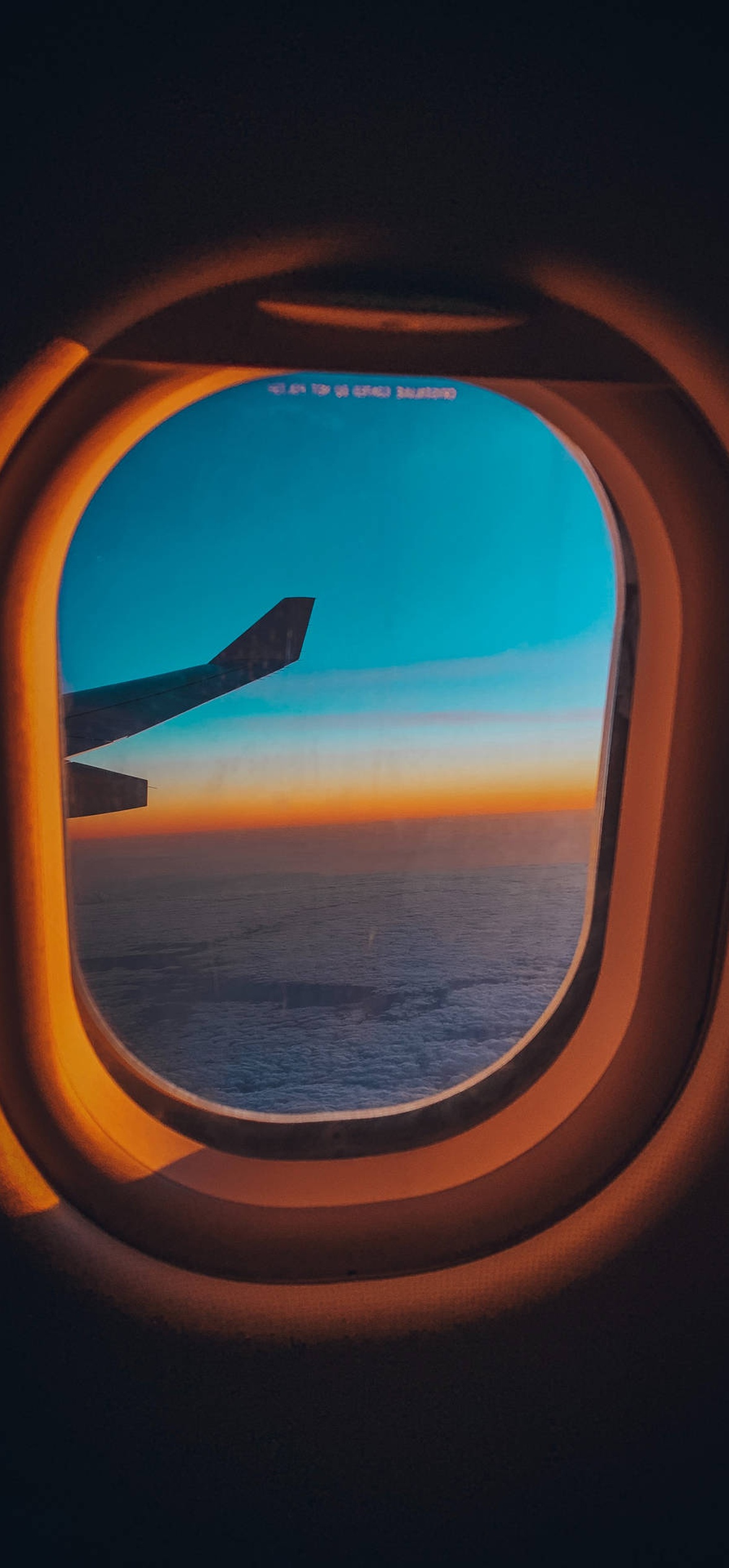 Sunset over ocean seen from airplane window with wing in view