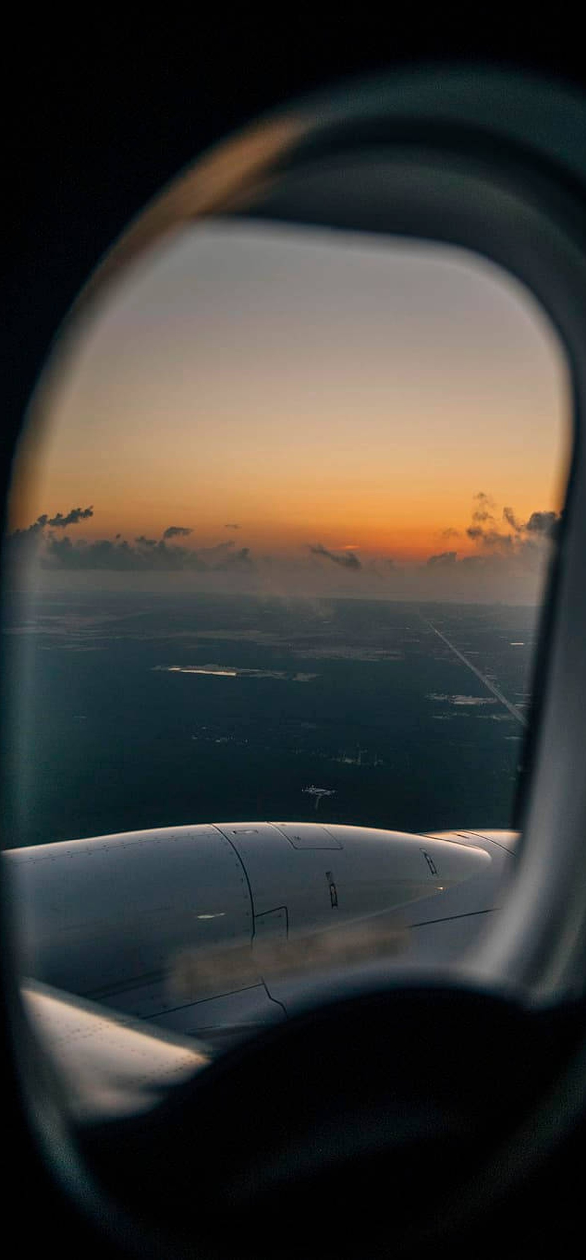 Aircraft wing and sunset viewed through airplane window