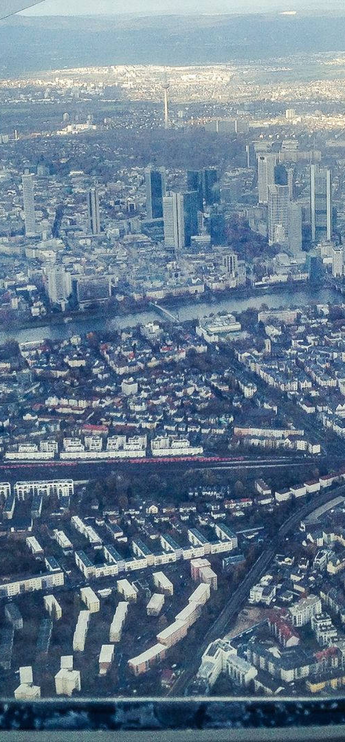 Aerial view of a dense city from an airplane window showing buildings and a river. – Ultra HD iPhone 18 Landscape Wallpapers