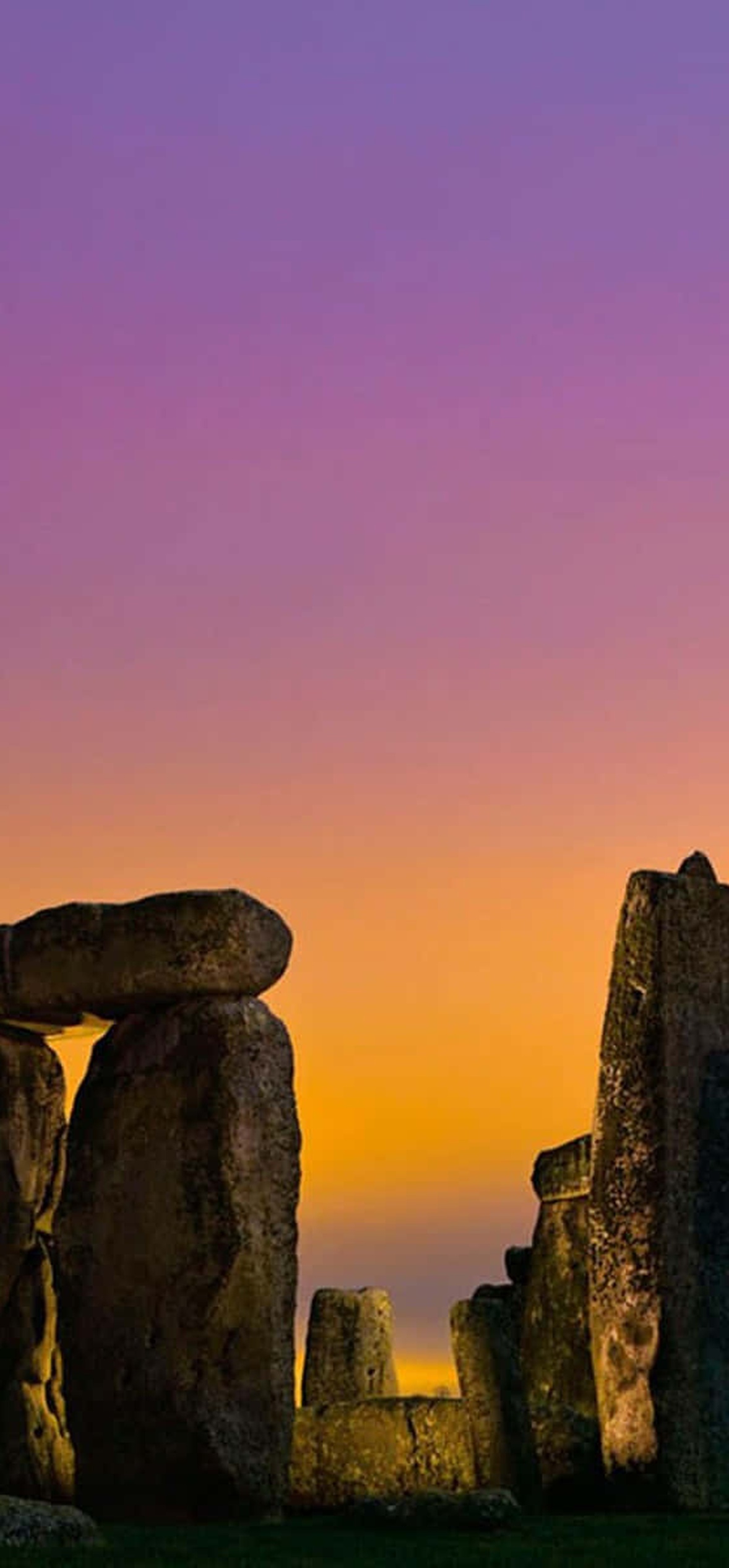 Stonehenge ancient monument silhouetted against a colorful twilight sky.