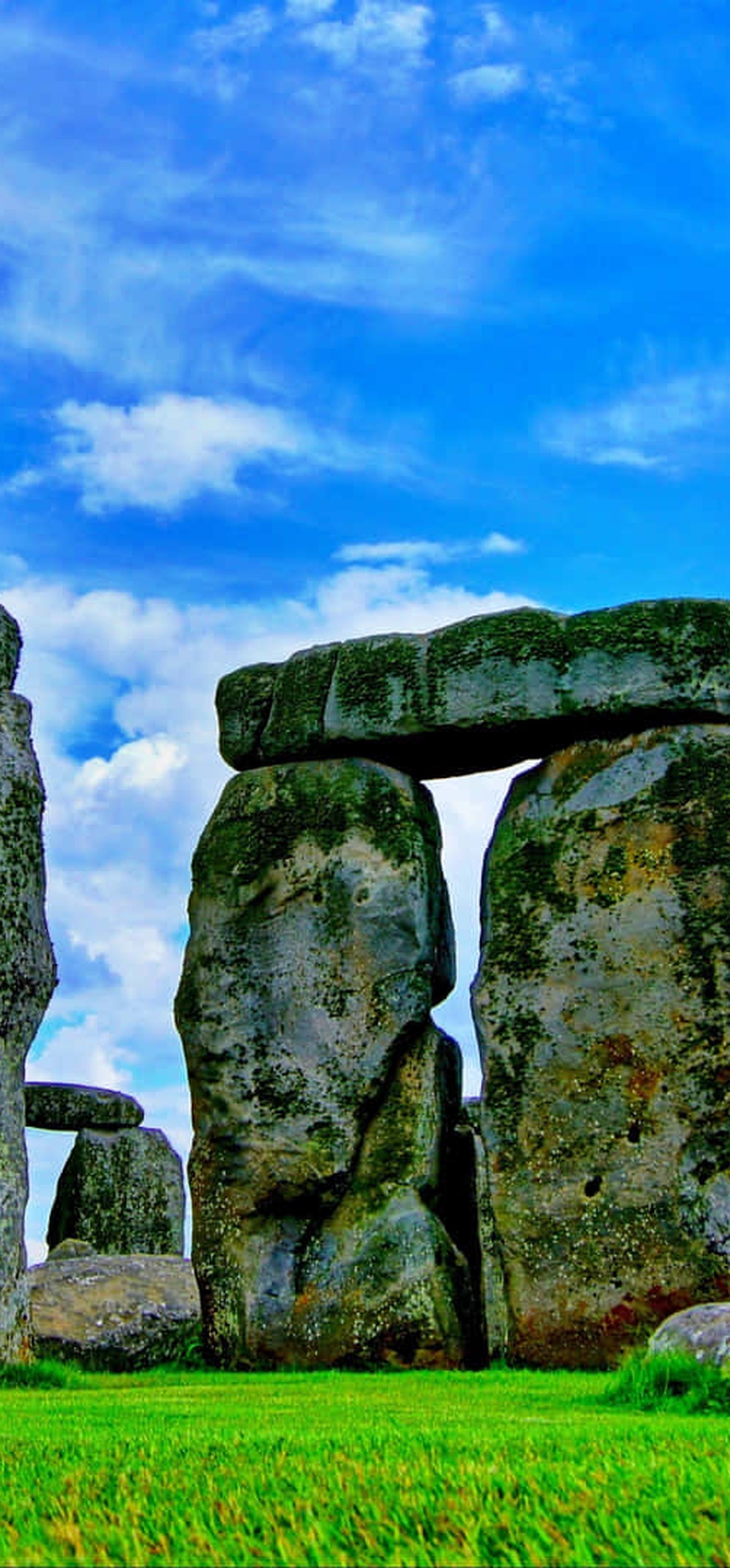 Stonehenge ancient stone circle under bright blue sky with green grass