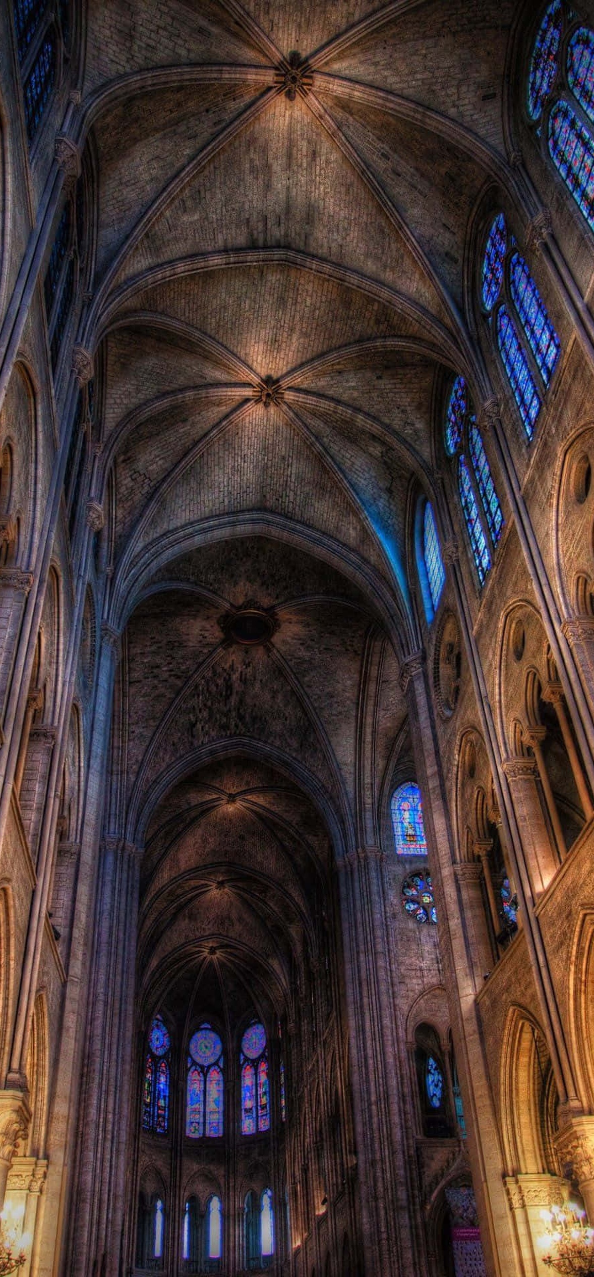 High vaulted stone cathedral interior with stained glass windows glowing.