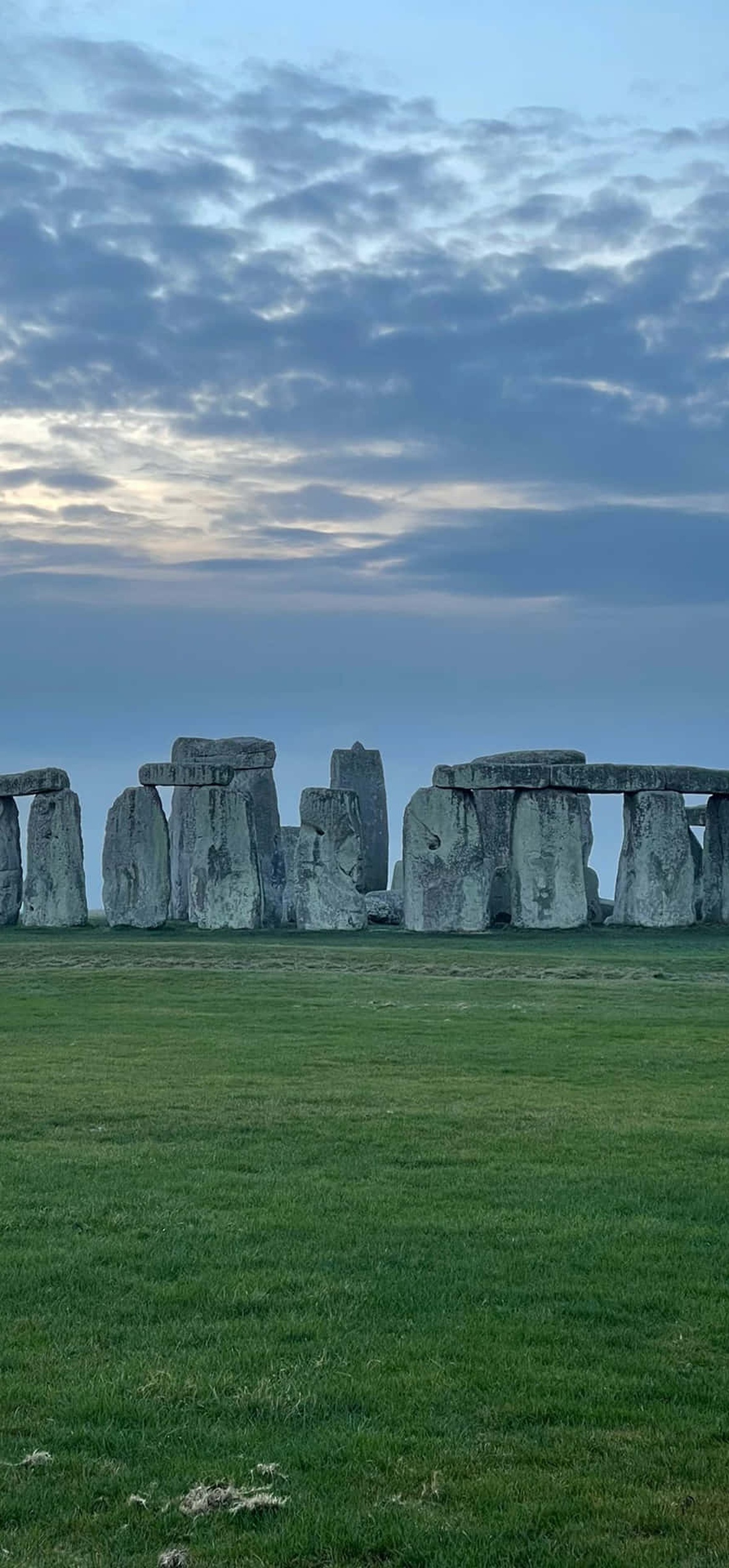 Stonehenge ancient stone circle at twilight with green grass and cloudy sky