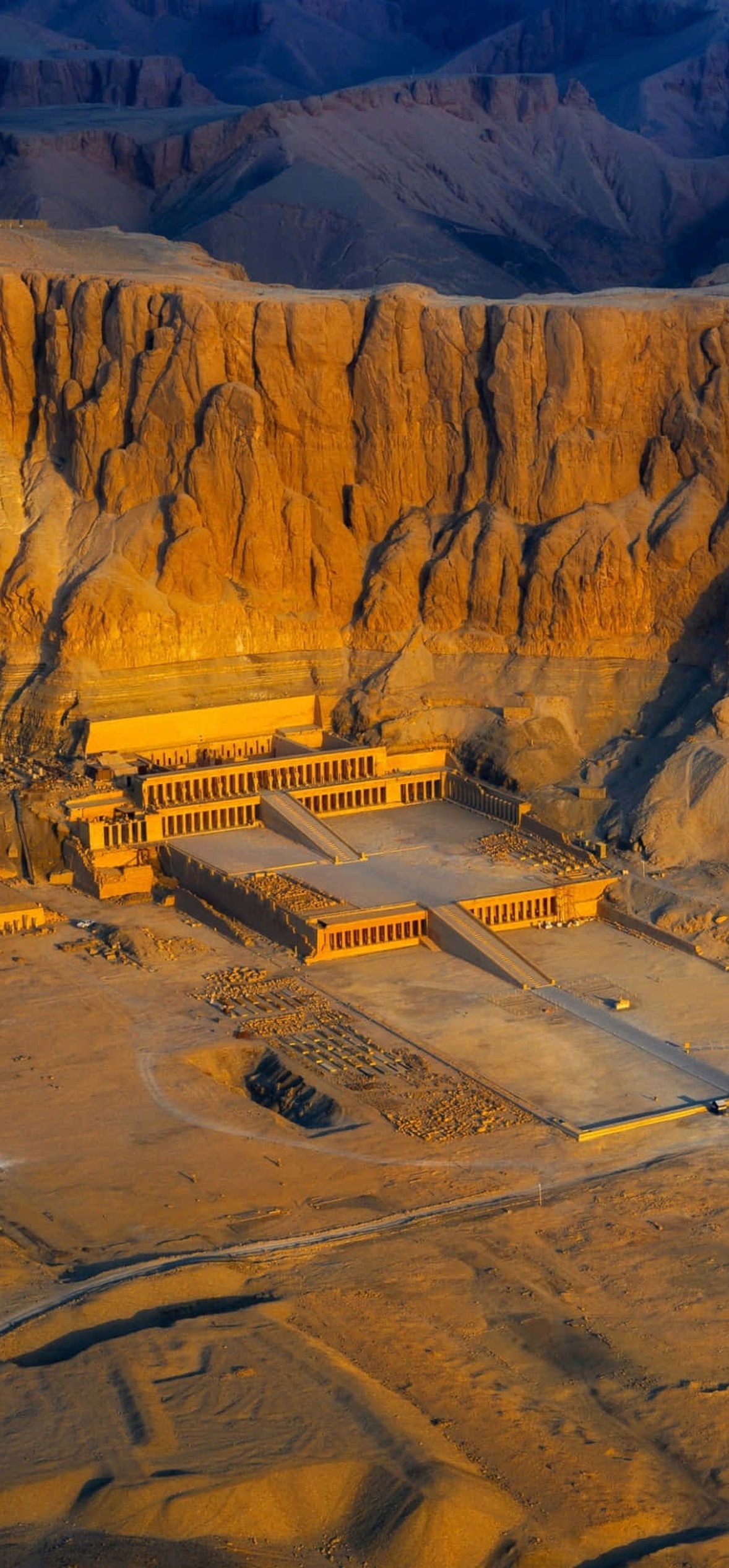 Ancient temple carved into desert cliffs bathed in golden sunset light.