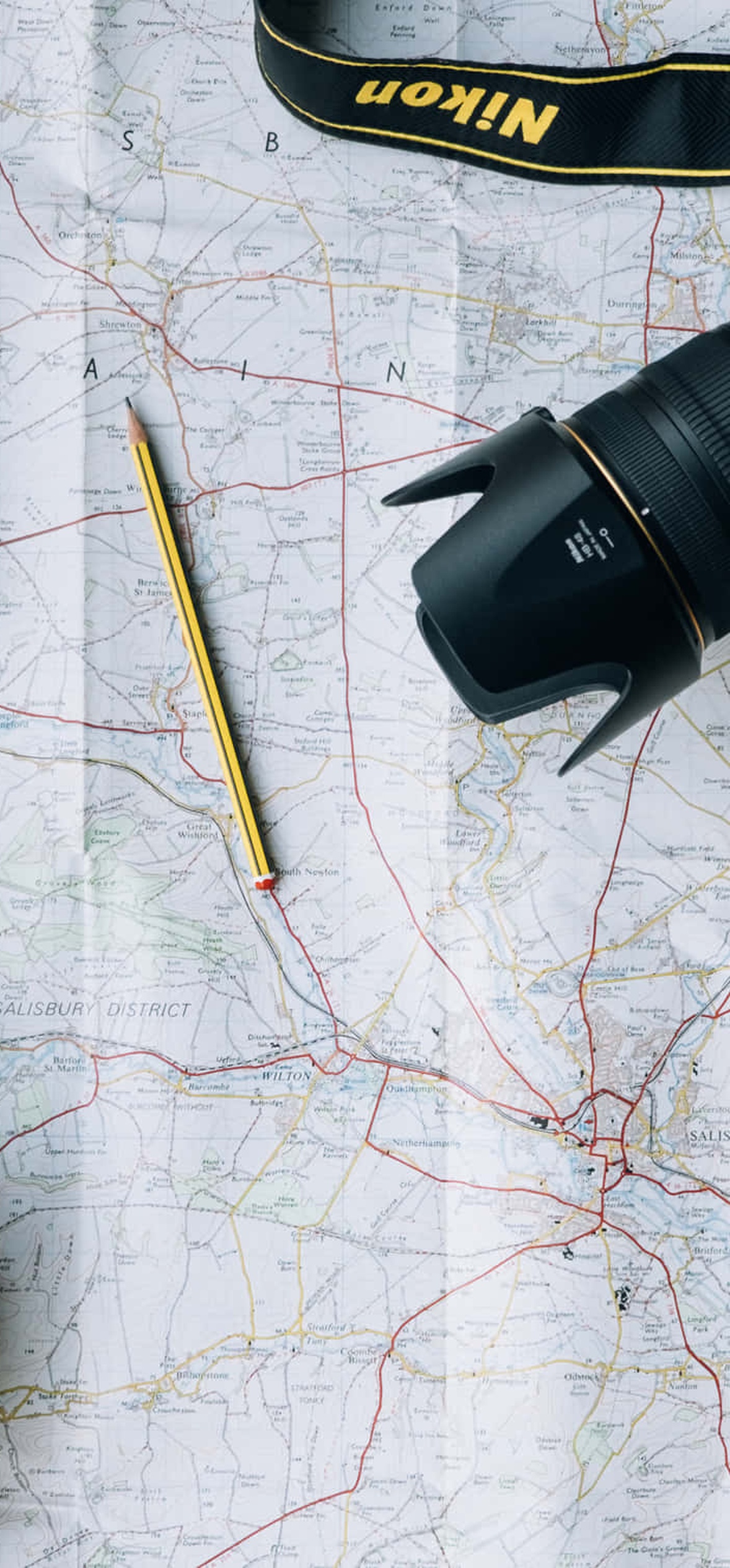 Travel gear including camera backpack and maps laid out for outdoor exploration.