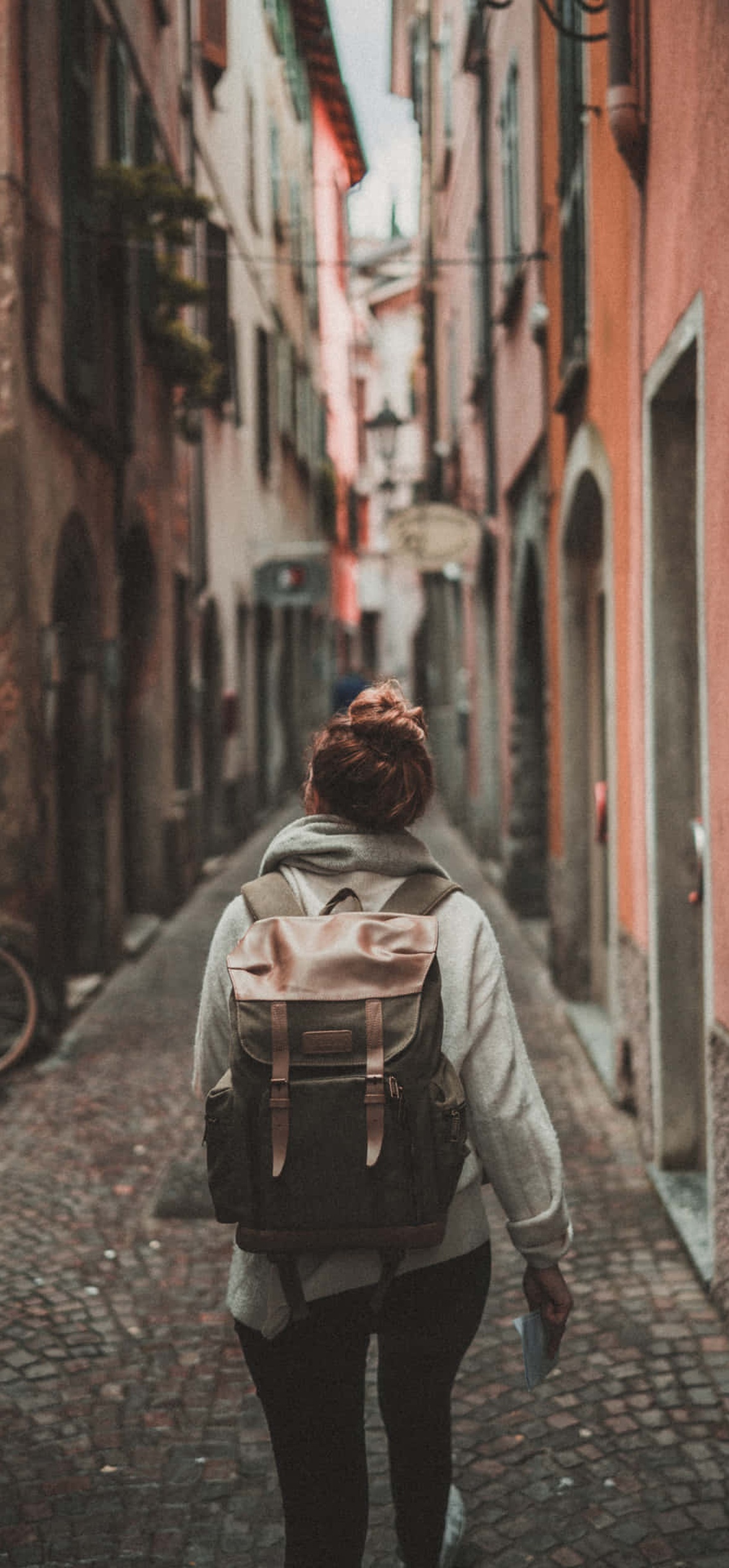 Person walking down narrow cobblestone street with colorful buildings